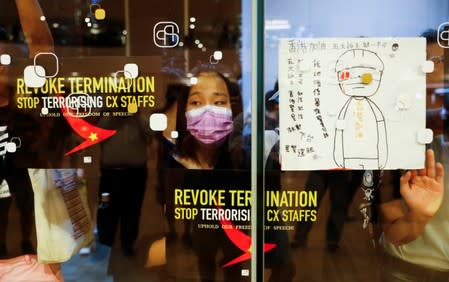 People paste placards on windows as they take part in a rally held by the Hong Kong Confederation of Trade Unions after a number of crew members in the aviation industry were let go for joining the anti-extradition bill protests, in Hong Kong