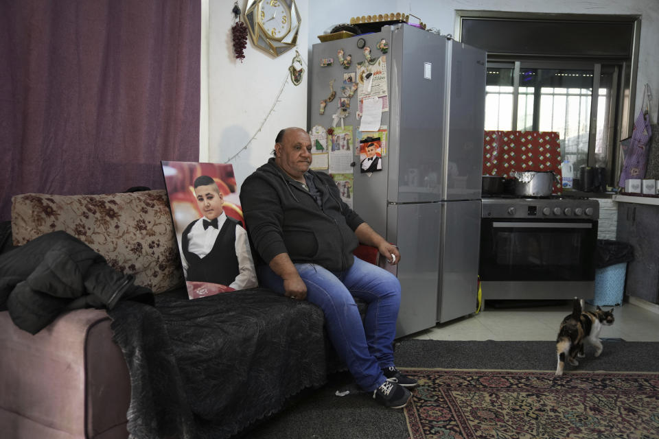Ali Halhouli se sienta junto a una foto de su hijo asesinado Rami Halhouli, en su casa del campo de refugiados de Shuafat en Jerusalén Oriental, el domingo 17 de marzo de 2024. Halhouli, de 12 años, murió baleado por un policía israelí cuando lanzaba fuegos artificiales el 12 de marzo. (AP Foto/Mahmoud Illean)