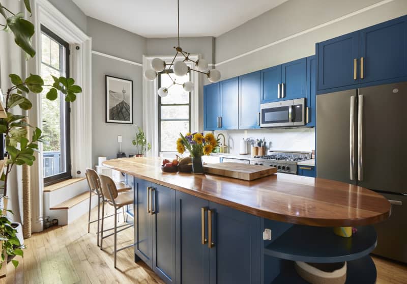 Blue cabinets in gray-painted kitchen with multi-armed pendant light hung over island.