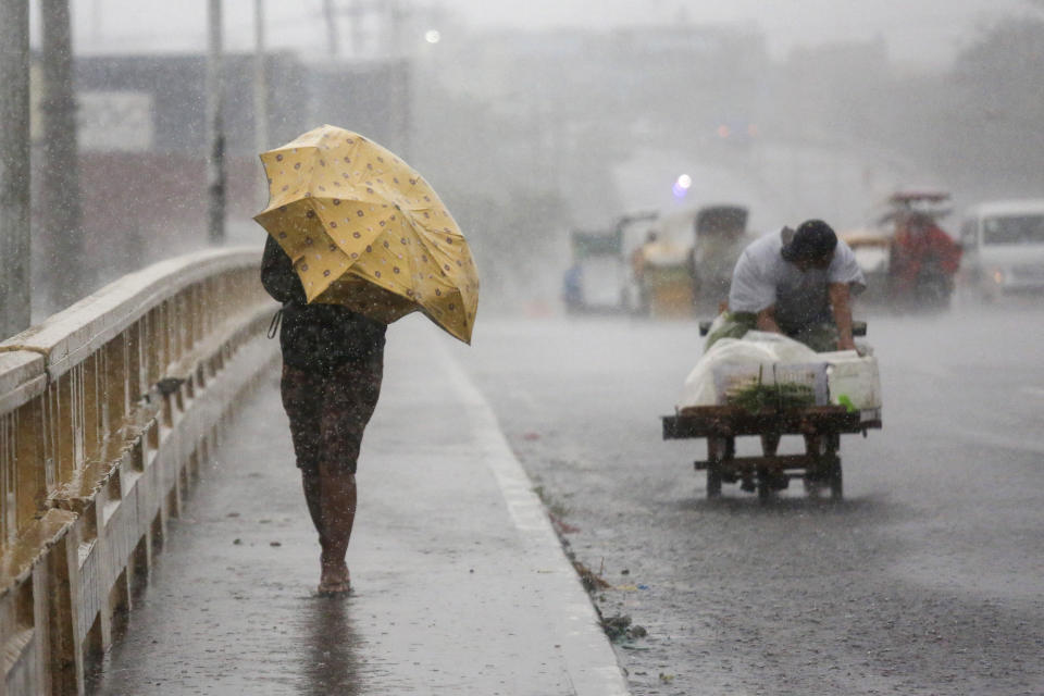 A woman uses an umbrella as she crosses a bridge under heavy rains brought by typhoon Vamco in Navotas City, Philippines on Thursday. Nov. 12, 2020. A typhoon swelled rivers and flooded low-lying areas as it passed over the storm-battered northeast Philippines, where rescuers were deployed early Thursday to help people flee the rising waters. (AP Photo/Basilio Sepe)