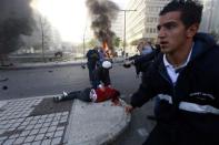 People run to help a wounded man as smoke rises from the site of an explosion in Beirut's downtown area December 27, 2013. The explosion rocked the Lebanese capital on Friday, causing an unknown number of casualties.The blast was heard across the city and a plume of black smoke was seen rising in the downtown business district near the Phoenicia Hotel. REUTERS/Jamal Saidi