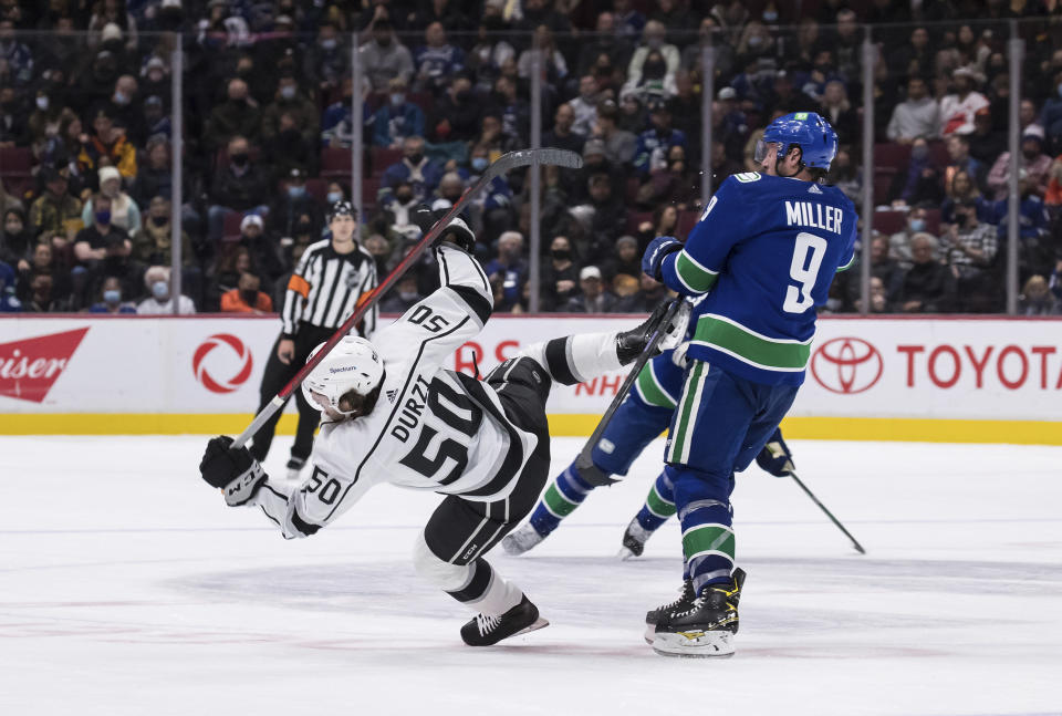 Vancouver Canucks' J.T. Miller (9) checks Los Angeles Kings' Sean Durzi (50) during the second period of an NHL hockey game in Vancouver, British Columbia, Monday, Dec. 6, 2021. (Darryl Dyck/The Canadian Press via AP)