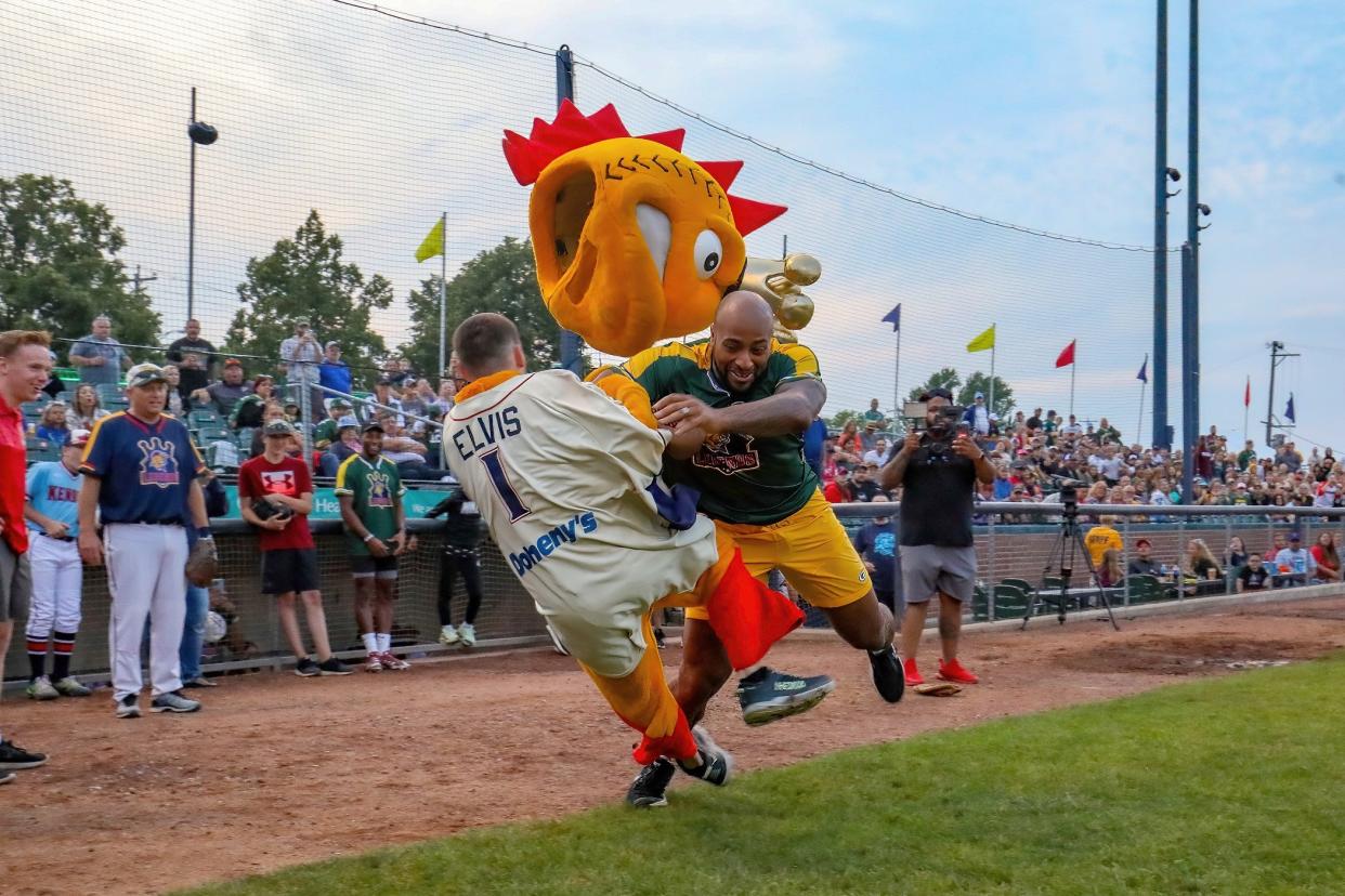 Kenosha Kingfish mascot Elvis gets taken down by Green Bay Packers running back AJ Dillon during an Oklahoma Drill at the Kingfish celebrity softball game July 16, 2022.