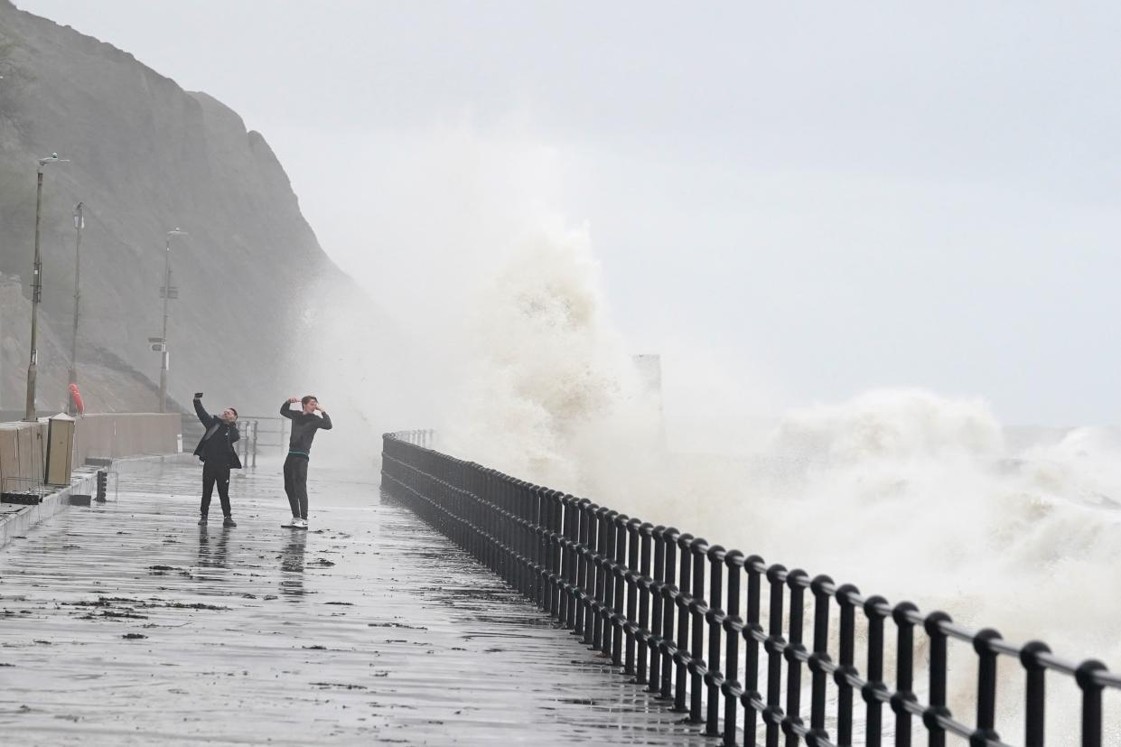 People photograph the waves crashing over the promenade in Folkestone, Kent (Gareth Fuller/PA Wire)