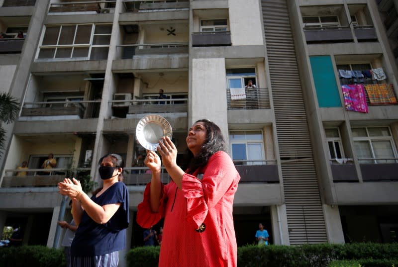 Residents clap and bang utensils to cheer for emergency personnel and sanitation workers who are on the frontlines in the fight against coronavirus, in Ahmedabad