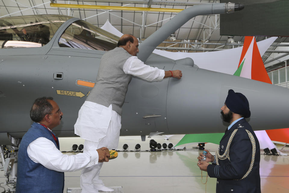 FILE- In this Oct. 8, 2019, file photo, Indian Defense Minister Rajnath Singh writes onto a Rafale jet fighter as a ritual gesture during an handover ceremony at the Dassault Aviation plant in Merignac, near Bordeaux, southwestern France. In India, the relationship between faith and science is complicated. Seeking comfort in the certainty of the past, Indians are tuning into re-runs of popular Hindu religious dramas, drawing on shared experiences of old times when most questions had answers. (AP Photo/Bob Edme, File)