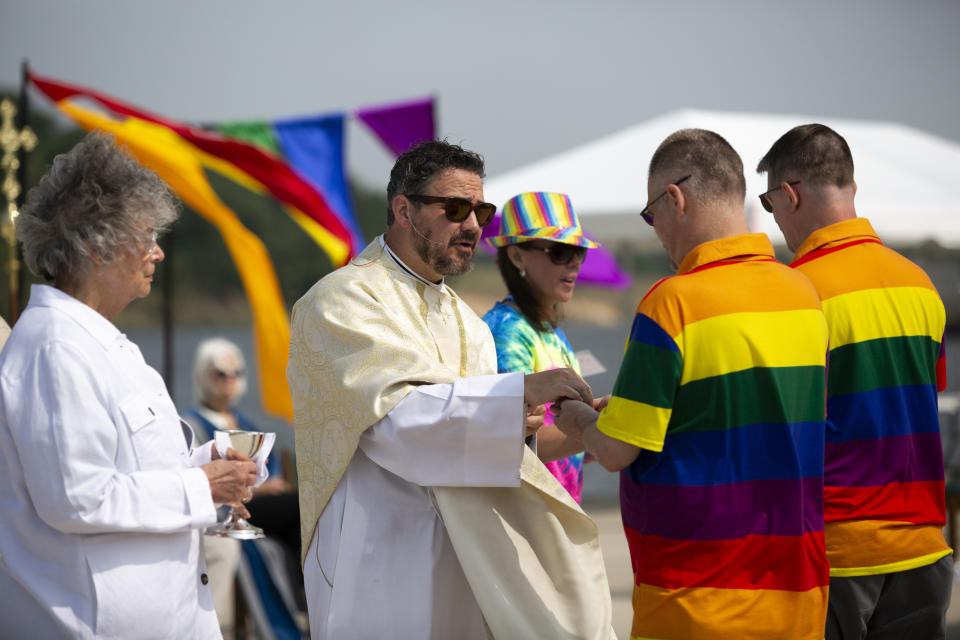 Rev. Dr. Jared Cramer of St. John's Episcopal Church hands out bread during Communion at a pride worship service at the Lynne Sherwood Waterfront Stadium in Grand Haven, Mich., on Saturday, June 10, 2023. The festival — which organizers had hoped would attract at least 500 attendees — drew thousands of people from all over who came to experience the first-time event's drag show, dance party and vendor-filled streets. (AP Photo/Kristen Norman)