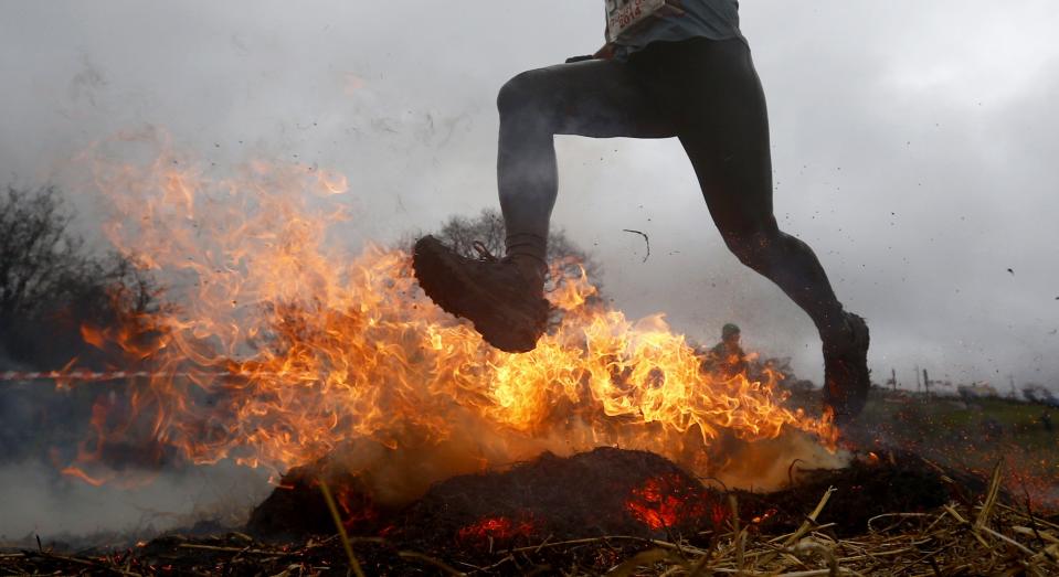 A competitor jumps across a burning obstacle during the Tough Guy event in Perton