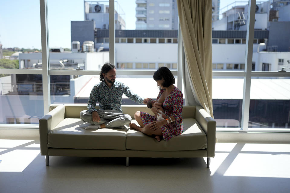 Maxim Levoshin sits with his wife Ekaterina Gordienko as she breastfeeds their newborn baby named Leo, in Buenos Aires, Argentina, Saturday, Feb. 18, 2023. Gordienko and Levoshin arrived in the Argentine capital in December. A study by immigration agents based on interviews with 350 newly arrived Russians concluded that most are married and largely well-off professionals who have remote jobs in finance and digital design or live off savings. (AP Photo/Natacha Pisarenko)