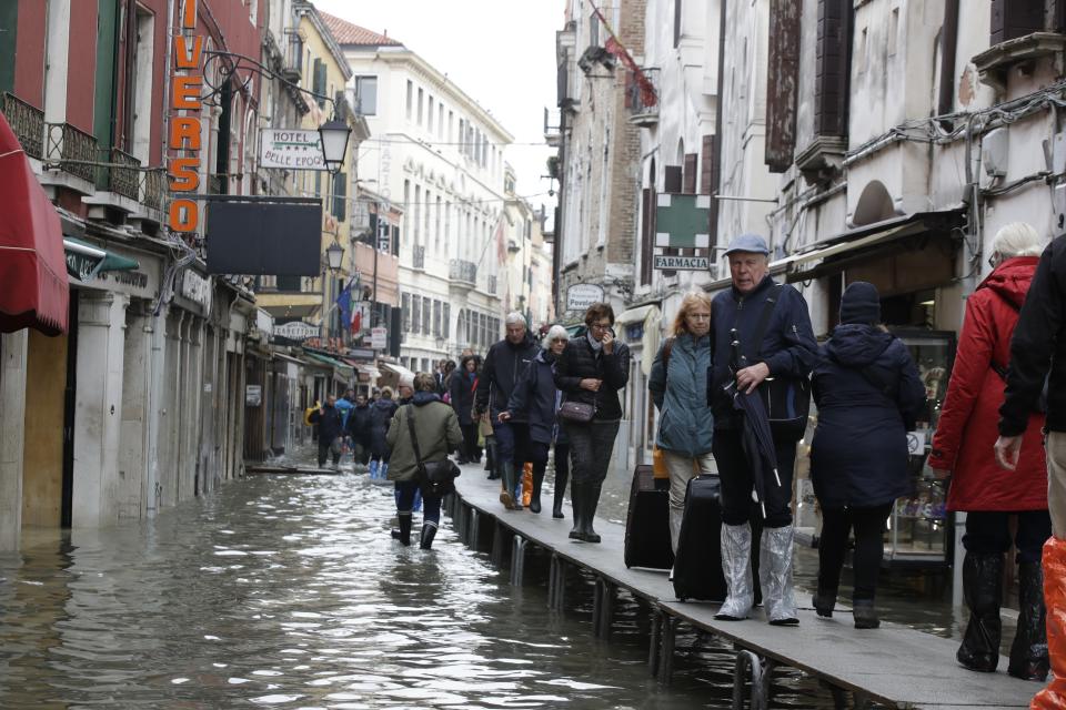 Tourist pull their suitcases along catwalks set up during a high tide, in Venice, Wednesday, Nov. 13, 2019. The high-water mark hit 187 centimeters (74 inches) late Tuesday, Nov. 12, 2019, meaning more than 85% of the city was flooded. The highest level ever recorded was 194 centimeters (76 inches) during infamous flooding in 1966. (AP Photo/Luca Bruno)