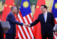 Malaysia's Prime Minister Mahathir Mohamad (L) shakes hands with China's Premier Li Keqiang at the end of a news conference at the Great Hall of the People in Beijing, China, August, 20, 2018. How Hwee Young/Pool via REUTERS