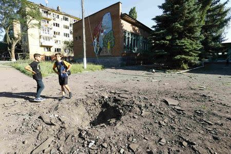 Boys stand near a shell crater outside a local school in the eastern Ukrainian town of Kramatorsk July 1, 2014. REUTERS/Shamil Zhumatov