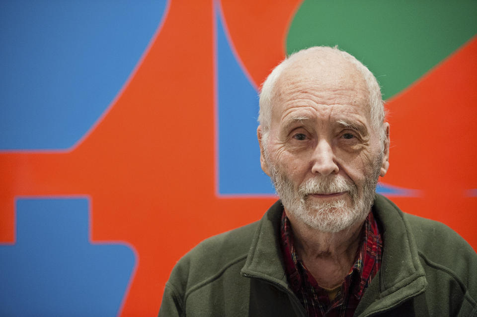 FILE - In this Sept. 24, 2013, file photo, artist Robert Indiana, known for his "LOVE" artwork series, poses in front of that painting at New York's Whitney Museum of American Art. Indiana's estate has reached a settlement that keeps intact a longstanding relationship with the copyright holder of the iconic "LOVE" series. Officials said Friday, June 11, 2021, that New York-based Morgan Art Foundation will work with the Maine-based Star of Hope Foundation, which aims to transform Indiana's island home in Maine into a museum. (AP Photo/Lauren Casselberry, File)