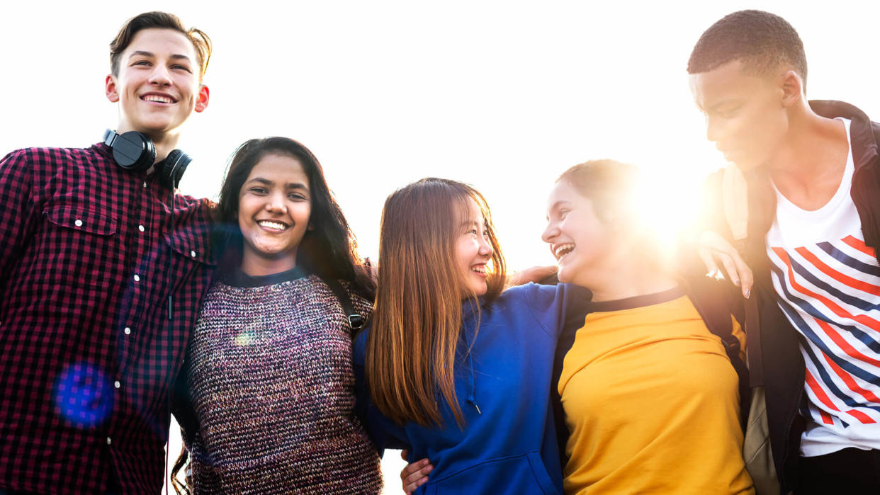 Group of school friends outdoors arms around one another togetherness and community concept.