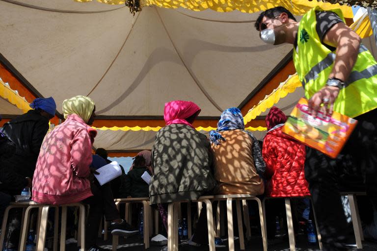 Migrants wait under a tent after disembarking from military ship "Bettica" following a rescue operation at sea on May 5, 2015 in the port of Salerno