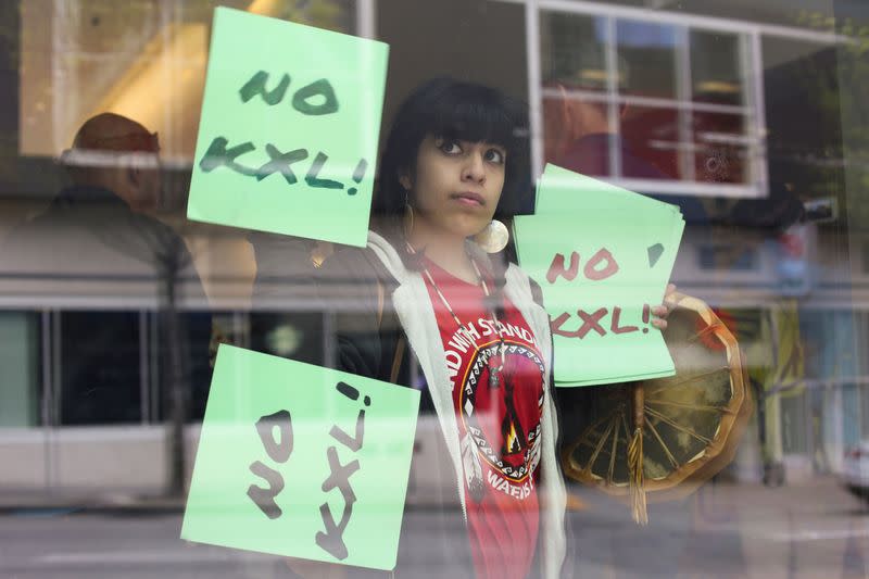 FILE PHOTO: A protester holds signs in opposition to the Keystone XL pipeline as she joins Native American leaders and climate activists demonstrating inside a Chase Bank location in Seattle