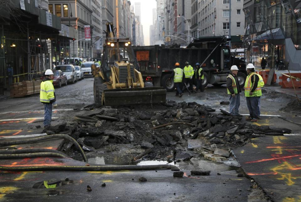 FILE- In this Jan. 15, 2016 file photo, members of a repair crew work around a hole in the middle of Fifth Avenue caused by a broken water main in New York. New York Gov. Andrew Cuomo has a plan to spend $2 billion to address water contamination and the state's aging, leaky pipes. (AP Photo/Seth Wenig, File)