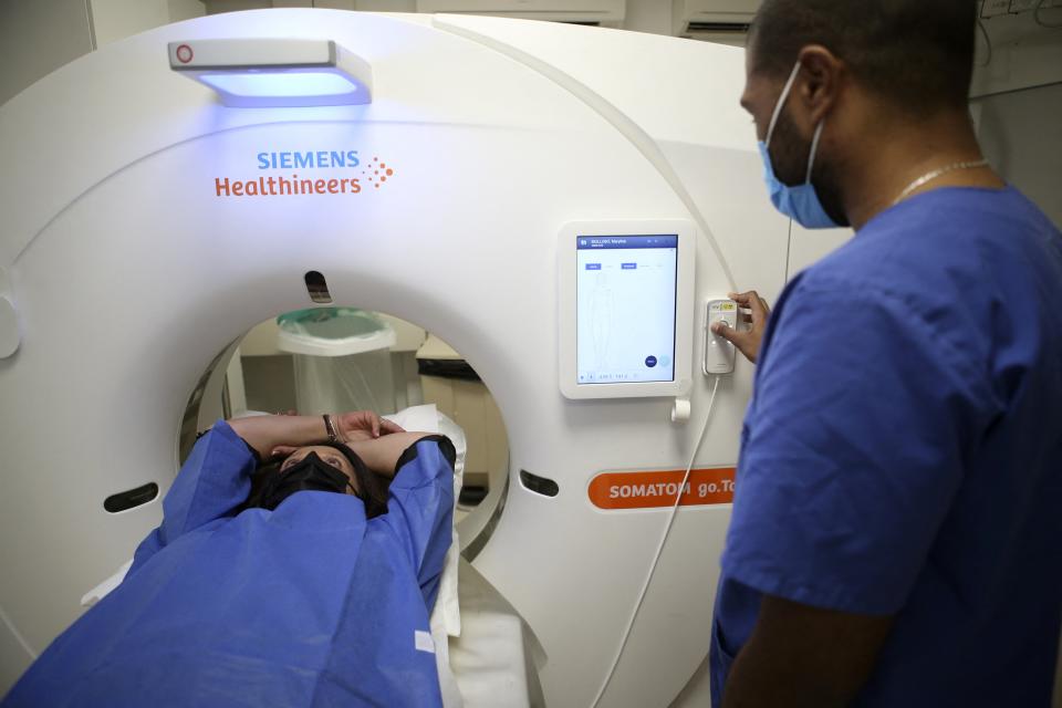 Medical Radiology Manipulator Ludovic Foy prepares a woman before her lung cancer screening on December 16, 2021. (Photo by Pascal POCHARD-CASABIANCA/AFP)