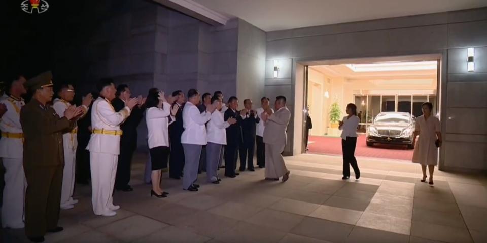 A row of people applaud as Kim Jong Un and his family arrive in a limousine at a banquet in Pyongyang on August 27, 2023.