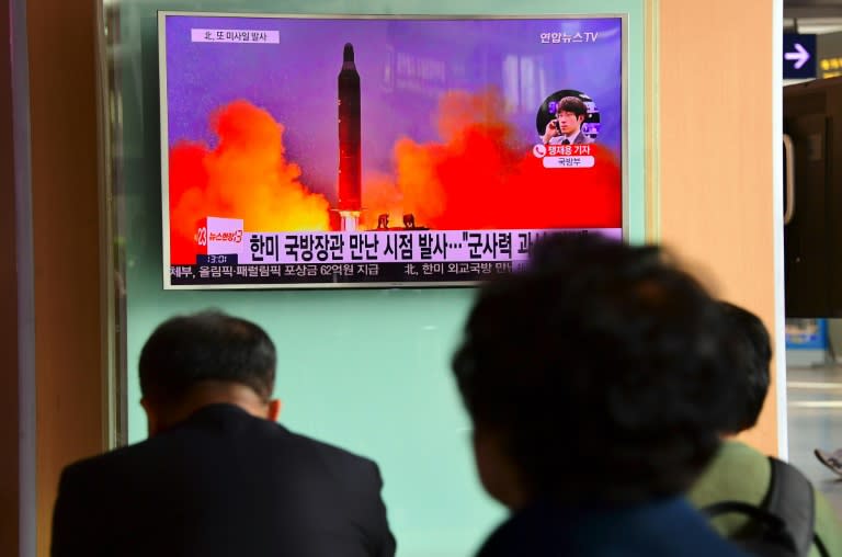 People watch a television news report showing file footage of North Korea's missile launch at a railway station in Seoul on October 20, 2016