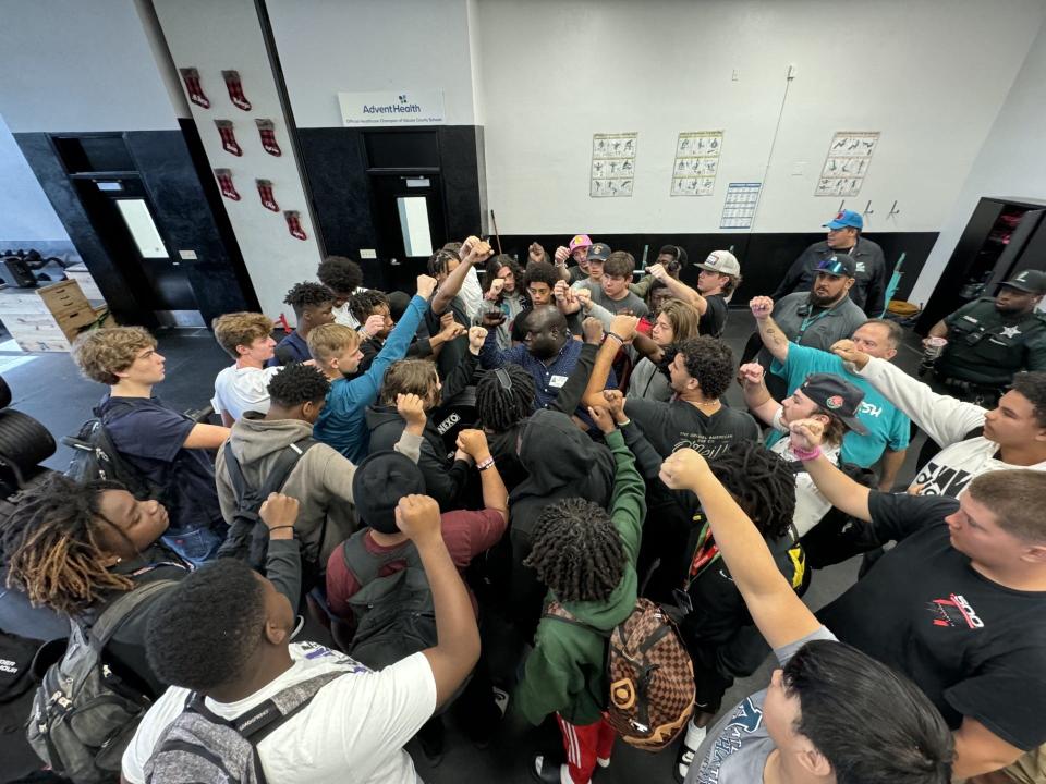 Tombe Thomas, center, met with Atlantic's football players Friday in the weight room after being named the Sharks' head coach.