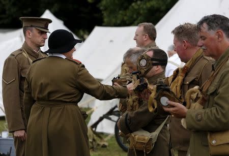 Senior construction manager Paul Barker (3rd R) portrays a Corporal in the Kings Royal Rifle Corps with the Rifles Living History Society as he participates in a gas mask check with Ciaran Watts (L), portraying a Lance Corporal, and Pat Taylor (2L) who is dressed as a member of the Women's Auxilliary Army Corps at the Colchester Military Tournament in Colchester, eastern England July 5, 2014. United by a fascination with military history and a fondness for dressing up, groups such as the Rifles Living History Society and the Queen's Own Royal West Kent Regiment Living History Group get together to re-create aspects of life during the First World War. Reuters photographer Luke MacGregor photographed members of the groups, both as they took part in living history events and at their day jobs. Picture taken July 5, 2014. REUTERS/Luke MacGregor