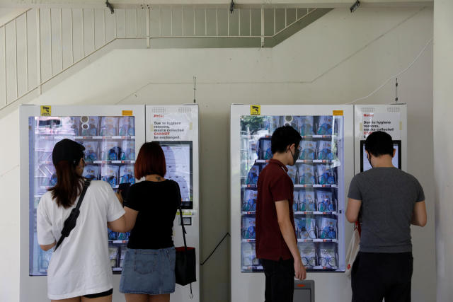 Residents collect free protective face masks from vending machines in their housing estate.