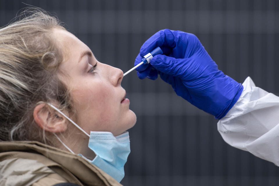 A woman gets a nasal swab at the corona test center at Central Station in Cologne, Germany, Friday, Oct. 23, 2020. According to the Robert Koch Institute, Germany's federal government agency and research institute responsible for disease control and prevention, the number of new infections with the corona virus in Cologne has risen to 120.1 per 100,000 inhabitants. (Marius Becker/dpa via AP)