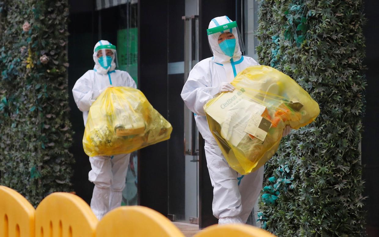 People in lab suits outside the hotel where the WHO investigative team were stationed - Thomas Peters/Reuters