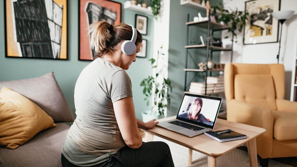 Woman teleconferencing with sister on laptop due to COVID-19 lockdown.