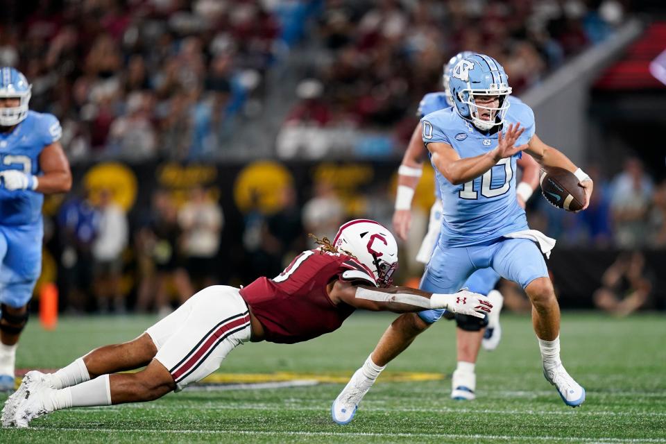 North Carolina quarterback Drake Maye, right, jumps away from a tackle-attempt by South Carolina linebacker Debo Williams during the first half of an NCAA college football game Saturday, Sept. 2, 2023, in Charlotte, N.C. (AP Photo/Erik Verduzco)