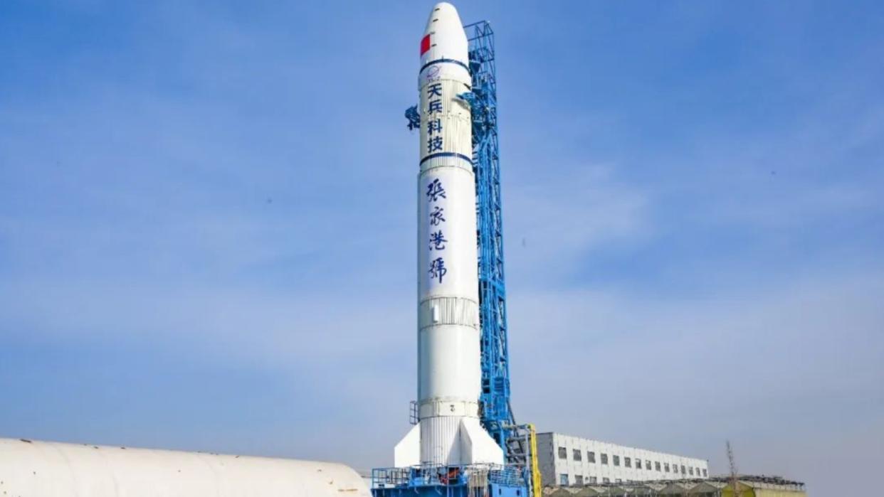  A white rocket stands upright on a launch pad. 