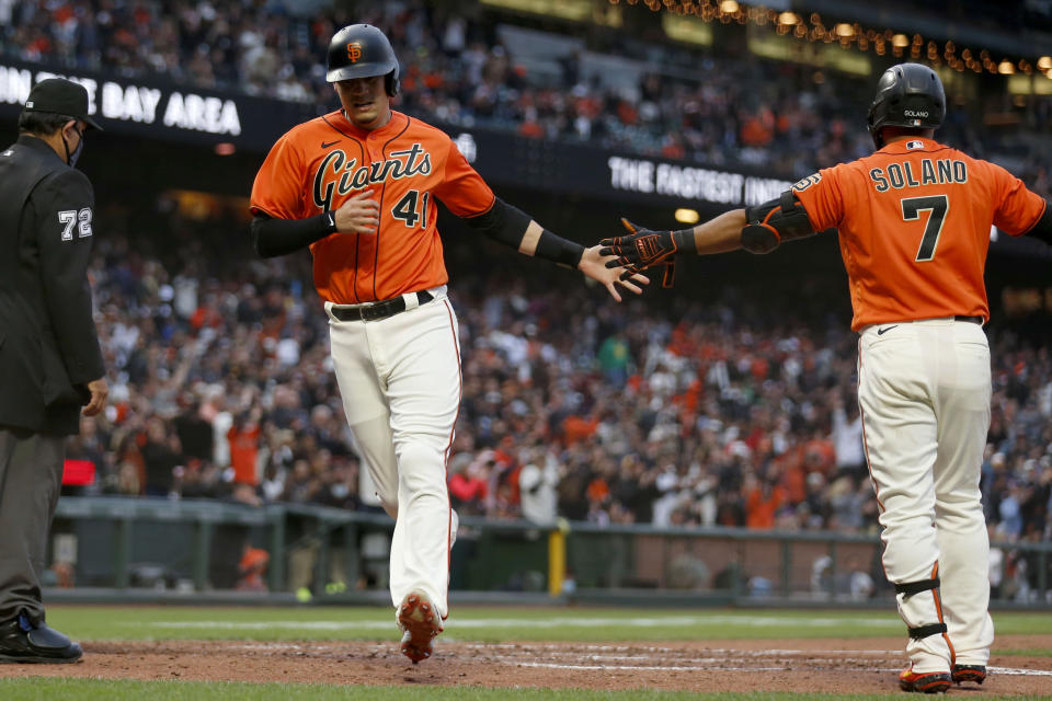 San Francisco Giants' Wilmer Flores, left, is congratulated by teammate Donovan Solano after scoring on a hit by Brandon Crawford against the Oakland Athletics during the fourth inning of a baseball game in San Francisco, Friday, June 25, 2021. (AP Photo/Jed Jacobsohn)