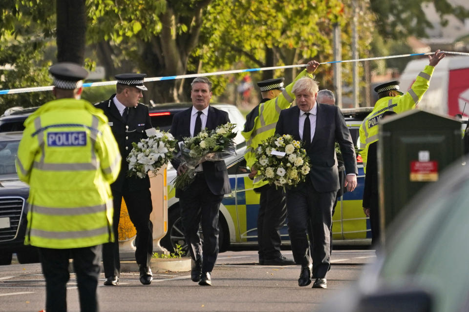 British Prime Minister Boris Johnson, right, and Leader of the Labour Party Sir Keir Starmer, second from right, carry flowers as they arrive at the scene where a member of Parliament was stabbed Friday, in Leigh-on-Sea, Essex, England, Saturday, Oct. 16, 2021. David Amess, a long-serving member of Parliament was stabbed to death during a meeting with constituents at a church in Leigh-on-Sea on Friday, in what police said was a terrorist incident. A 25-year-old man was arrested in connection with the attack, which united Britain's fractious politicians in shock and sorrow. (AP Photo/Alberto Pezzali)