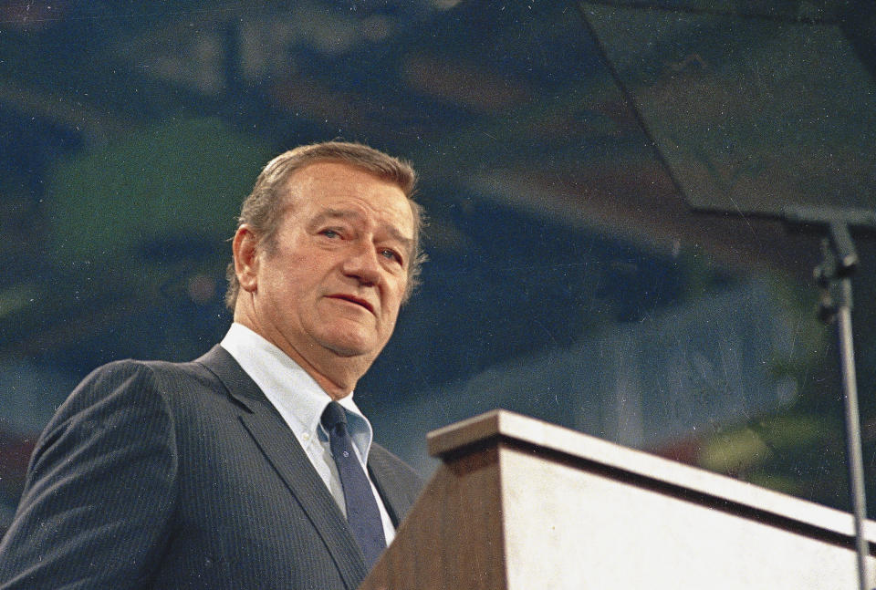 FILE - In this 1968 file photo, actor John Wayne looks on. In the latest move to change place names in light of U.S. racial history, leaders of Orange County’s Democratic Party are pushing to drop film legend Wayne’s name, statue and other likenesses from the county’s airport because of his racist and bigoted comments. (AP Photo/File)