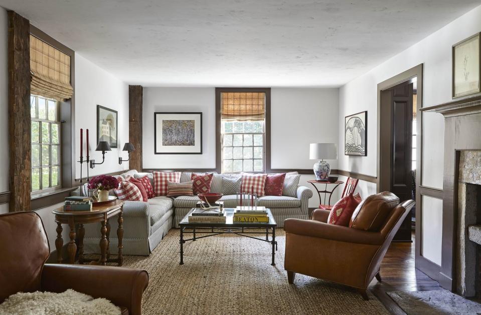 the casual living room is furnished with antique french leather armchairs and a sprawling sectional sofa covered in a vintage ticking stripe and several of the pillows were crafted with fabrics the owners picked up on their travels