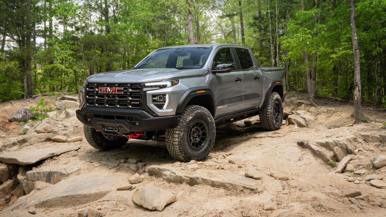 a black truck parked on a rocky area with trees in the background