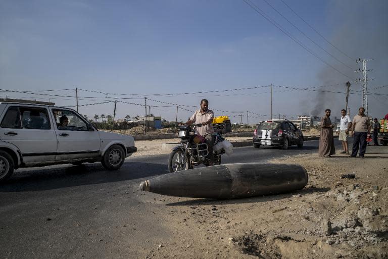 Palestinian motorists pause to inspect an Israeli shell laying unexploded in the central gaza town of Deir al-Balah, on August 1, 2014