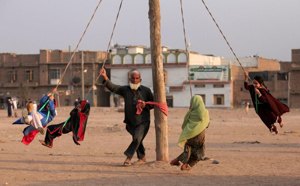 A man spins children on a home made merry-go-round in a vacant lot in Peshawar