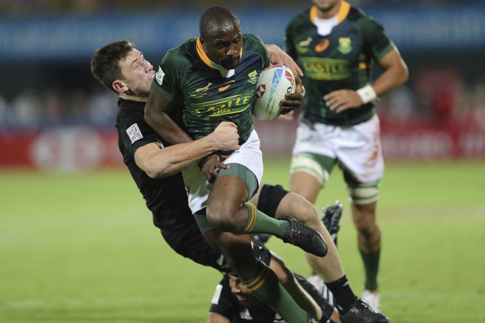 South Africa's Siviwe Soyizwapi runs with the ball as New Zealand's players try to stop him in the final match of the Emirates Airline Rugby Sevens in Dubai, United Arab Emirates, Saturday, Dec.7, 2019. (AP Photo/Kamran Jebreili)