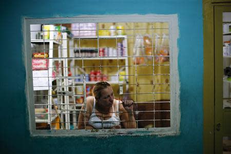 A woman looks out of a window at her shop in a corridor inside the "Tower of David" skyscraper in Caracas February 6, 2014. REUTERS/Jorge Silva