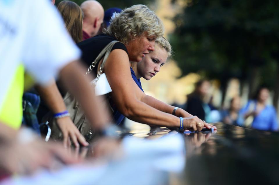 Gail Silke and her niece Erica Tierney (R) trace the name of Gail's brother Steven Bristoll, a police officer, at the 9/11 Memorial during ceremonies marking the 12th anniversary of the 9/11 attacks on the World Trade Center in New York September 11, 2013. (REUTERS/Alejandra Villa)