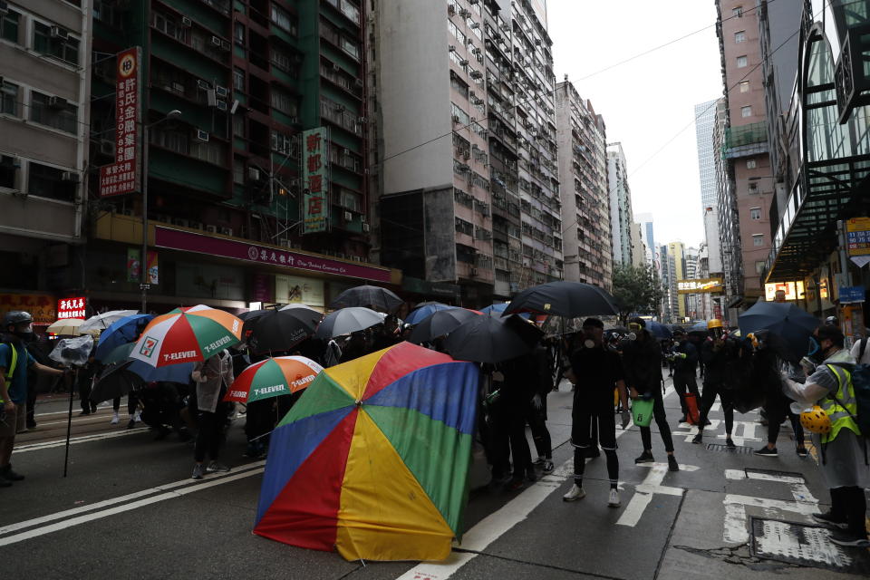 Protestors use umbrellas to take cover as they clash with police in Hong Kong, Sunday, Oct. 6, 2019. Shouting "Wearing mask is not a crime," tens of thousands of protesters braved the rain Sunday to march in central Hong Kong as a court rejected a second legal attempt to block a mask ban aimed at quashing violence during four months of pro-democracy rallies. (AP Photo/Vincent Thian)