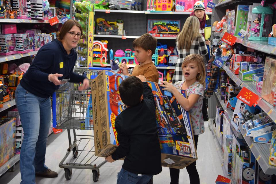 Two students work together to carry a big Hot Wheels set to their cart on Monday, Dec. 11, 2023. Charlevoix Elementary School raised more than $20,000 to spend at Walmart, buying toys for children in need this holiday season.