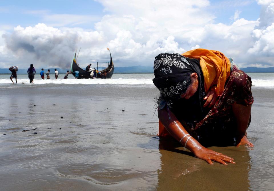 An exhausted Rohingya refugee woman touches the shore after crossing the Bangladesh-Myanmar border by boat through the Bay of Bengal, in Shah Porir Dwip, Bangladesh September 11, 2017.