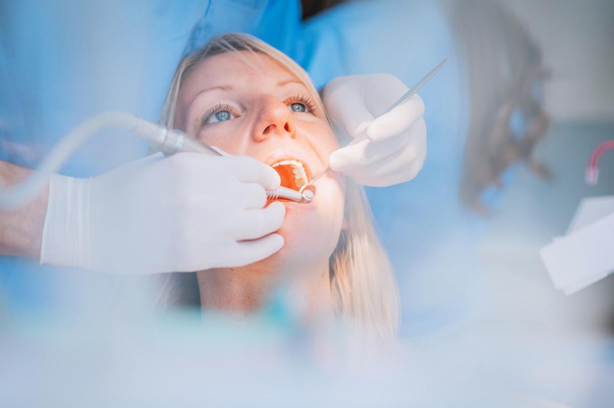 Close-up of a dentist's hands working on the patient's teeth.