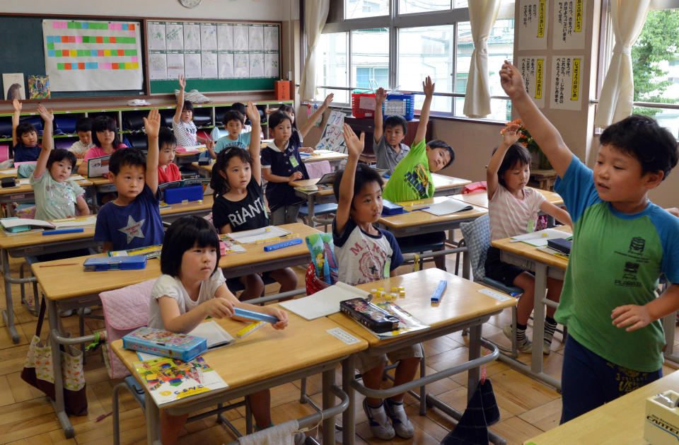 Six-year-old Japanese elemetary student Seishi Nishida raises his hand with classmates at school in Tokyo on June 11, 2013. 