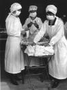 Red Cross workers of Boston, Massachussetts remove bundles of masks designated for American soldiers, while other nurses are busy making them, March 1919. (Photo by PhotoQuest/Getty Images)