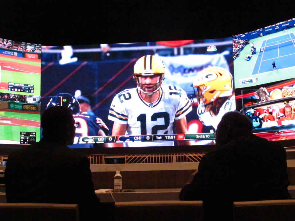 FILE - In this Sept. 5, 2019, file photo, people watching the first NFL game of the season in the sports betting lounge at Bally's casino in Atlantic City N.J. The NFL draft starting on Thursday, April 23, 2020, is expected to be the most heavily wagered-on draft ever, mainly because virtually all major sporting events have been postponed due to the coronavirus outbreak. (AP Photo/Wayne Parry, File)