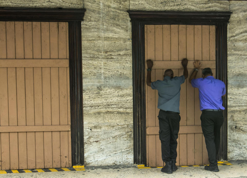 Residents board up a storefront pharmacy as they prepare for the arrival of Tropical Storm Dorian, in Bridgetown, Barbados, Monday, Aug. 26, 2019. Much of the eastern Caribbean island of Barbados shut down on Monday as Dorian approached the region and gathered strength, threatening to turn into a small hurricane that forecasters said could affect the northern Windward islands and Puerto Rico in upcoming days. (AP Photo/Chris Brandis)